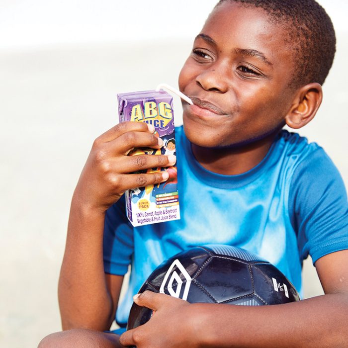 Active young child drinking Rugani 100% ABC Juice 330ml through a straw